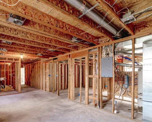 Home interior work in progress with exposed framing and newly installed electrical wiring and outlets
